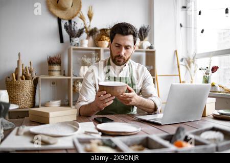 Adult ceramic shop owner using laptop while working in store. Stock Photo