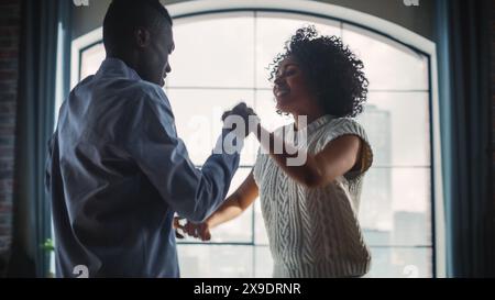 Close Up Portrait of Multiethnic Couple in Casual Clothes Dancing and Having a Date at Home in Loft Apartment. Happy Boyfriend and Girlfriend Creatively Dance, Both are Adorable and Smiling. Stock Photo