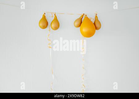 Deflated yellow balloons on golden string white background. After party holiday concept Stock Photo