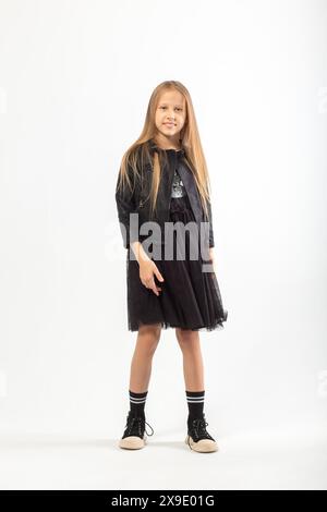 A full-length portrait of a young girl with long brown hair dressed in a hooligan style on white background in studio. Stock Photo