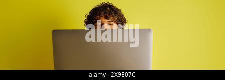 A man in a vibrant Indian outfit sits concentrated in front of a laptop computer. Stock Photo