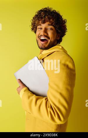 Handsome man with curly hair holding a laptop. Stock Photo