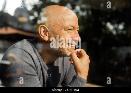 Elderly man with a thoughtful expression through a glass window Stock Photo