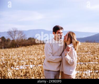 Couple enjoying a sunny day in a harvested field, mountains behind Stock Photo