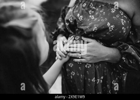 Young Girl holding Mother's Pregnant Belly Stock Photo