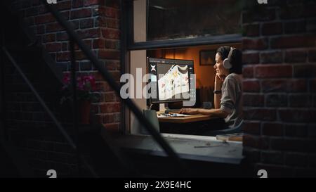 View From Outside The Window in the Apartment: Female Footwear Designer Creating and Rendering 3d Model of Shoes and Working on Powerful Desktop Computer. Shoe Production Procedure Concept. Stock Photo