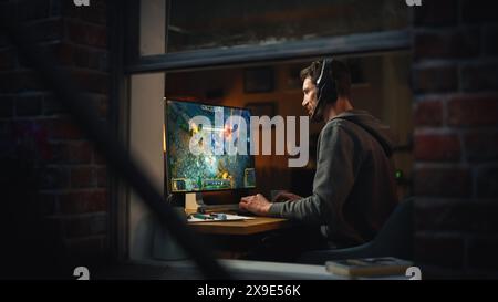 Focused Middle Aged Male Gamer Playing Online Video Game on Personal Computer. Guy Enjoying Fantasy RPG Game with Role Playing Character Casting Spells, Destroy Enemies. Shot from Outdoors. Stock Photo