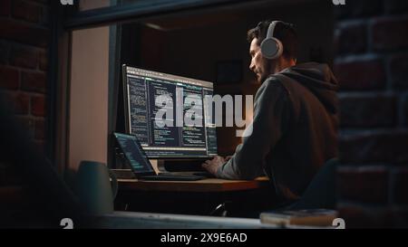 Professional Software Developer Writing Mock-up Code with Basic Programming Language. Program Engineer. Information Technology Specialist. Remote Work Concept. View From Outdoors into Window. Stock Photo