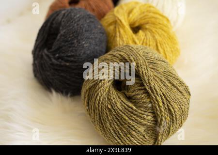 close-up photography of olive green tweed wool yarn skein on white lambskin fur background in natural light Stock Photo