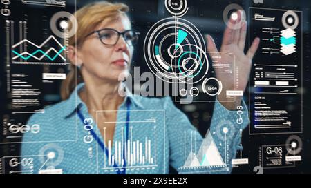 Adult Female Engineer Using Futuristic Augmented Reality Software Interface for Managing Data Center Work Projects. Specialist Researching Performance Data Graphs with Different Parameters. Stock Photo