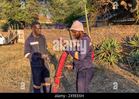 installing optic fiber outdoors, two african technicians, in residential home area Stock Photo