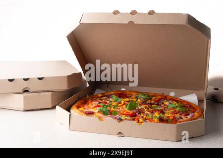 Large Pizza in open carton box on kitchen table closeup view Stock Photo