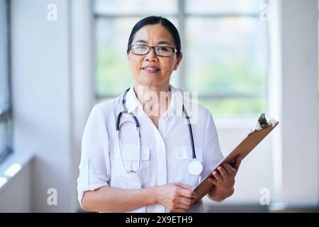 Confident Female Doctor Holding Clipboard in Hospital Corridor Stock Photo