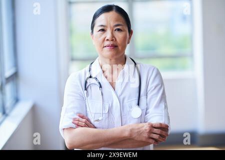Confident Female Doctor Standing In Hospital With Stethoscope Stock Photo