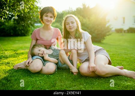 Cute big sisters cuddling with their toddler brother. Adorable teenage ...