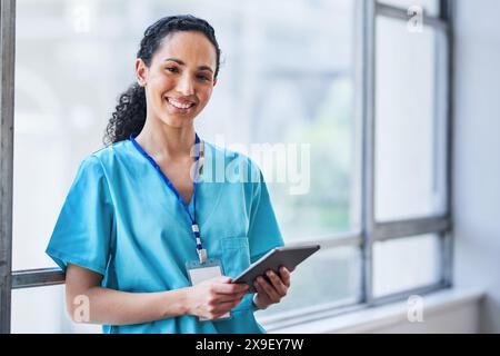 Friendly Female Doctor Smiling and Using Tablet in Modern Hospital Setting Stock Photo