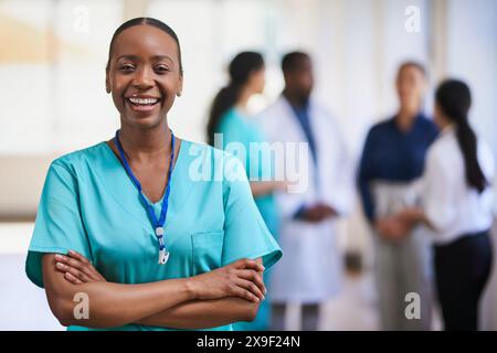 Confident Female Doctor Smiling with Medical Team in Background in Modern Hospital Stock Photo