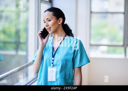 Female Doctor Talking on the Phone in a Hospital Setting, Smiling and Engaged Stock Photo