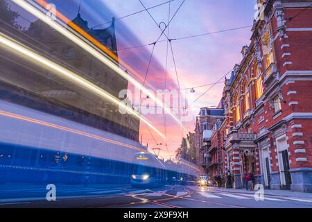 A tram passes along the Marnixstraat in Amsterdam, the Netherlands pm 27 May 2024 under a dramatic sky at twilight. Stock Photo