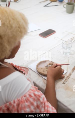 A vertical of a African American woman at a master class on making pottery clay Stock Photo