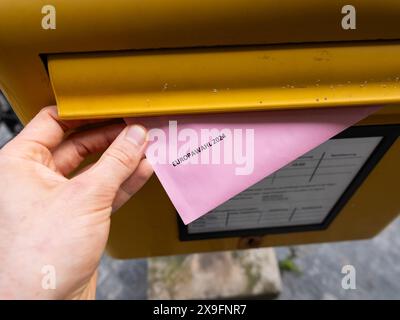 Postal voting for the European Election 2024. Posting the envelope with the ballot paper into a postbox in Germany. Casting a ballot for the EU. Stock Photo