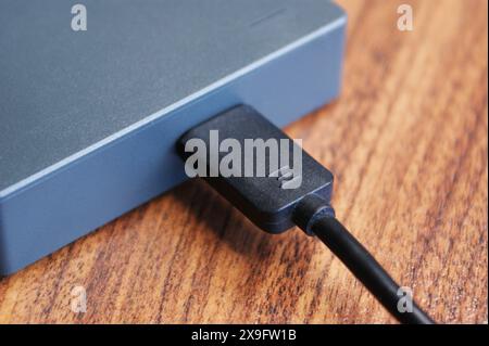 External hard drive on dark wooden table with cable attached. Stock Photo
