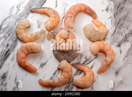 Raw shelled shrimp on white marble streaked with black Stock Photo