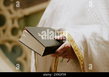 Closeup of hand of unrecognizable elderly Catholic priest holding prayer book standing outdoors Stock Photo