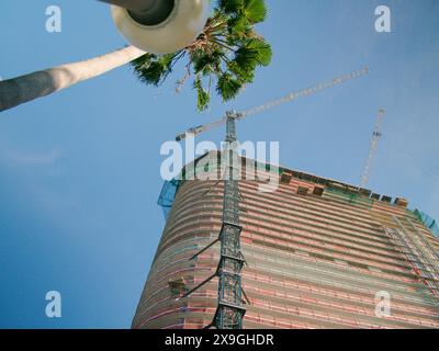 View up with street pole foreground to multi-story parking garage, building and cranes under construction. Blue sky and orange fencing. No people Stock Photo