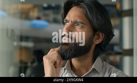 Close-up concentrated pensive thoughtful Indian man male guy businessman creative developer freelance programmer thinking about business idea planning Stock Photo