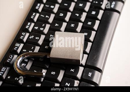 Close up a An open padlock on a computer keyboard illuminated by blue light. Stock Photo