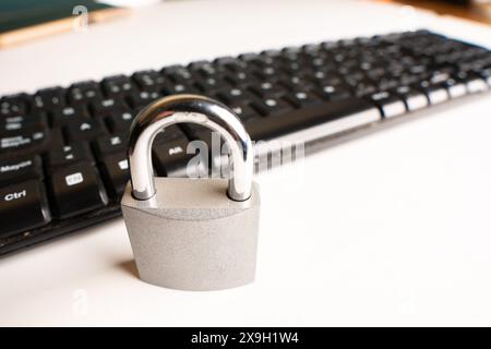 A closed padlock next to a computer keyboard on a white background with copy space Stock Photo