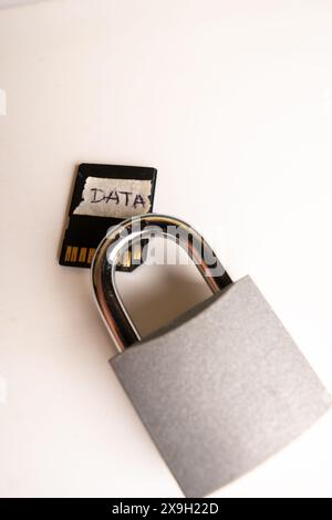 A closed padlock next to a memory card with the label "DATA" written on it, on a white background. Stock Photo