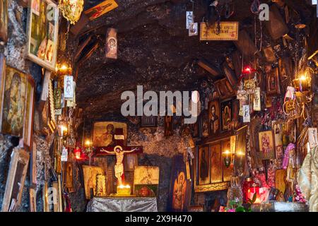 Rock Chapel, Archangel Michael Panormitits, Illuminated altar with a crucifix of Christ surrounded by icons and paintings in a cave, Old Town of Stock Photo