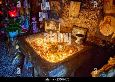 Rock Chapel, Archangel Michael Panormitits, Illuminated altar with burning candles in a cave, surrounded by icons and religious decorations, Old Town Stock Photo