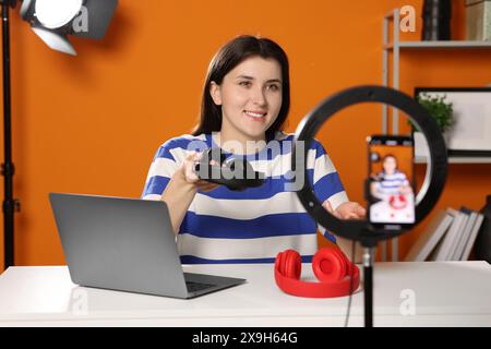 Smiling technology blogger recording video review about headphones at home Stock Photo