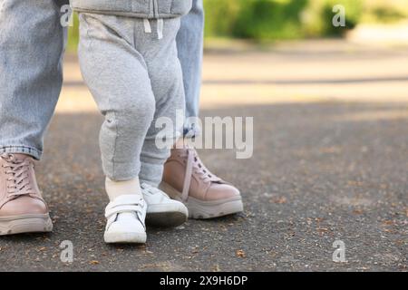 Mother teaching her baby how to walk outdoors, closeup. Space for text Stock Photo