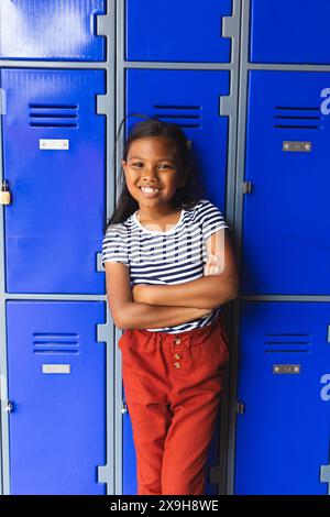 In school, young biracial female teacher holding a tablet smiles in the ...