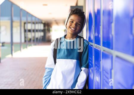 Biracial boy stands by school lockers, with copy space Stock Photo