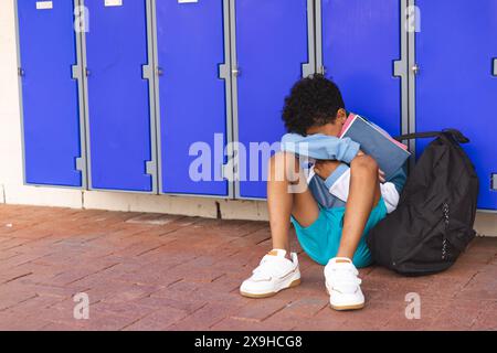 Biracial boy sits alone at school, with copy space Stock Photo