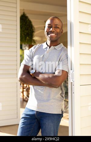 Young African American man stands confidently outside, arms crossed in casual wear Stock Photo