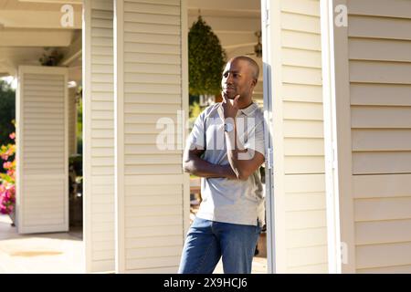 Outdoors, young African American man standing on porch, looking thoughtful Stock Photo