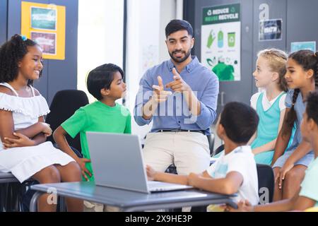 In school, Asian male teacher explaining to diverse group of young students in the classroom Stock Photo