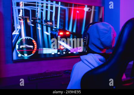 A biracial young female wearing headphones, playing video games at home Stock Photo