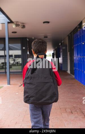 In school, young biracial male student is walking outdoors Stock Photo