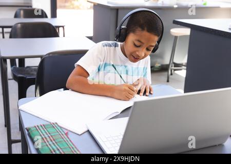 Biracial boy studies intently at school using a laptop Stock Photo