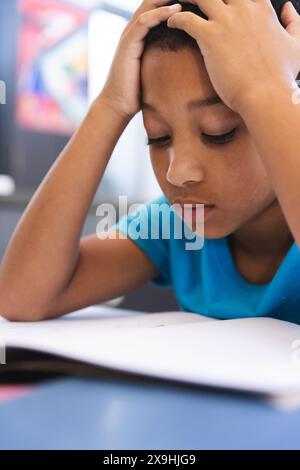 Biracial boy studies intently in the classroom at school Stock Photo