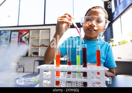 Biracial boy conducts an experiment in a science classroom at school Stock Photo