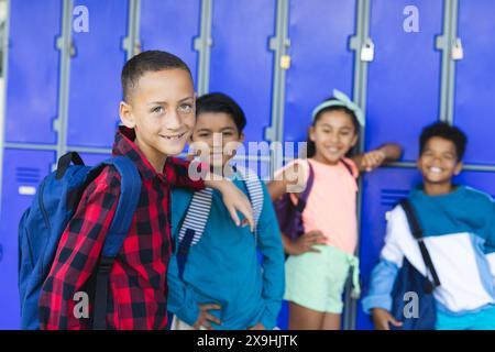 Diverse children stand by school lockers, smiling Stock Photo