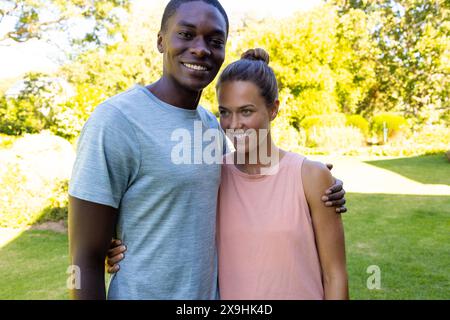 A diverse young couple standing outside, smiling at camera Stock Photo